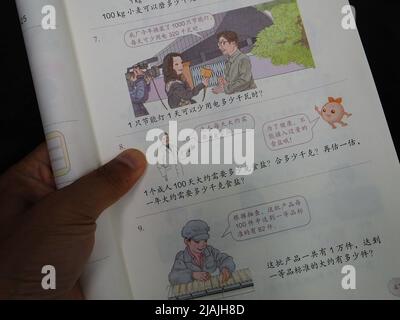 YICHANG, CHINA - 31. MAI 2022 - Ein Bürger zeigt die Illustrationen des zweiten Bandes des veröffentlichten Mathe-Lehrbuchs der vierten Klasse für Grundschulen Stockfoto