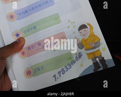 YICHANG, CHINA - 31. MAI 2022 - Ein Bürger zeigt die Illustrationen des zweiten Bandes des veröffentlichten Mathe-Lehrbuchs der vierten Klasse für Grundschulen Stockfoto