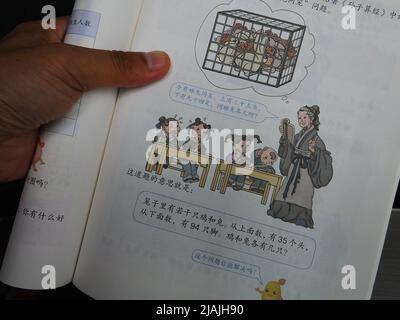 YICHANG, CHINA - 31. MAI 2022 - Ein Bürger zeigt die Illustrationen des zweiten Bandes des veröffentlichten Mathe-Lehrbuchs der vierten Klasse für Grundschulen Stockfoto