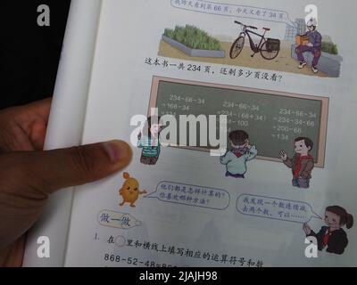 YICHANG, CHINA - 31. MAI 2022 - Ein Bürger zeigt die Illustrationen des zweiten Bandes des veröffentlichten Mathe-Lehrbuchs der vierten Klasse für Grundschulen Stockfoto