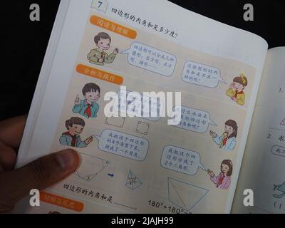 YICHANG, CHINA - 31. MAI 2022 - Ein Bürger zeigt die Illustrationen des zweiten Bandes des veröffentlichten Mathe-Lehrbuchs der vierten Klasse für Grundschulen Stockfoto