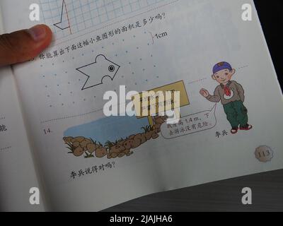 YICHANG, CHINA - 31. MAI 2022 - Ein Bürger zeigt die Illustrationen des zweiten Bandes des veröffentlichten Mathe-Lehrbuchs der vierten Klasse für Grundschulen Stockfoto