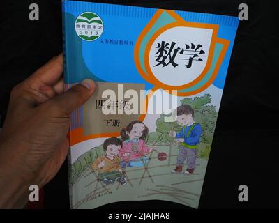 YICHANG, CHINA - 31. MAI 2022 - Ein Bürger zeigt die Illustrationen des zweiten Bandes des veröffentlichten Mathe-Lehrbuchs der vierten Klasse für Grundschulen Stockfoto
