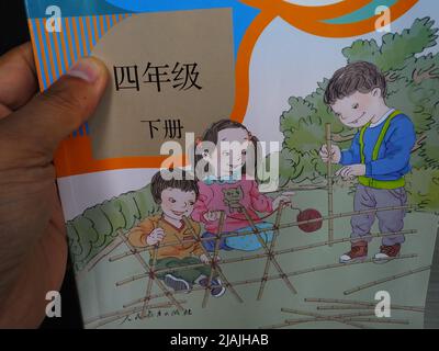 YICHANG, CHINA - 31. MAI 2022 - Ein Bürger zeigt die Illustrationen des zweiten Bandes des veröffentlichten Mathe-Lehrbuchs der vierten Klasse für Grundschulen Stockfoto