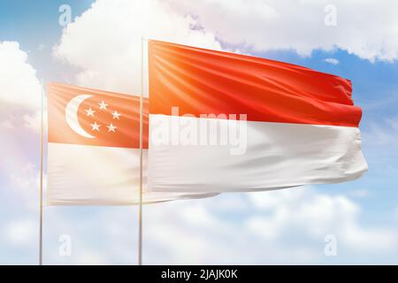 Sonniger blauer Himmel und Flaggen von indonesien und singapur Stockfoto