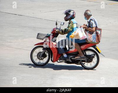 SAMUT PRAKAN, THAILAND, APR 02 2022, Ein Taxifahrer auf einem Motorrad fährt mit einem älteren Mann. Das Moto-Taxi trägt einen Passagier Stockfoto