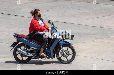 SAMUT PRAKAN, THAILAND, APR 02 2022, Eine Frau mit Gesichtsmaske fährt ein Motorrad Stockfoto