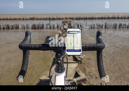 Der Lenker des Fahrrads mit falscher Navigation steht am Rande eines abgerissenen Weges mit Meereshorizont Stockfoto