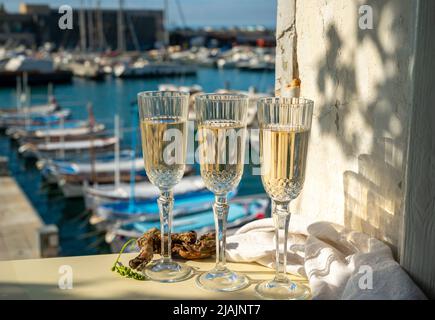 Drei Gläser französischer Champagner Sekt und Blick auf bunte Fischerboote im alten Hafen von Cassis, Provence, Frankreich, Sommerfest in PR Stockfoto