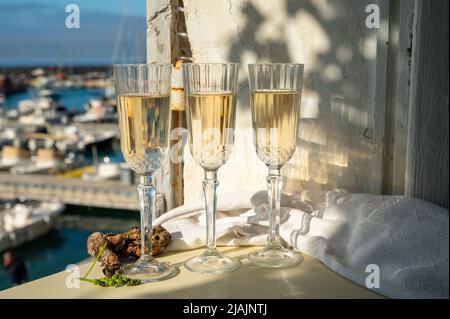 Drei Gläser französischer Champagner Sekt und Blick auf bunte Fischerboote im alten Hafen von Cassis, Provence, Frankreich, Sommerfest in PR Stockfoto