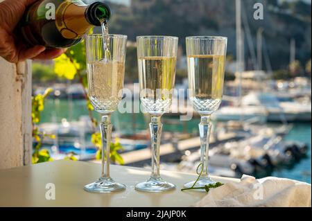 Drei Gläser französischen Champagner-Sekt und Blick auf bunte Fischerboote im alten Hafen von Cassis, Provence, Frankreich, Sommer Stockfoto