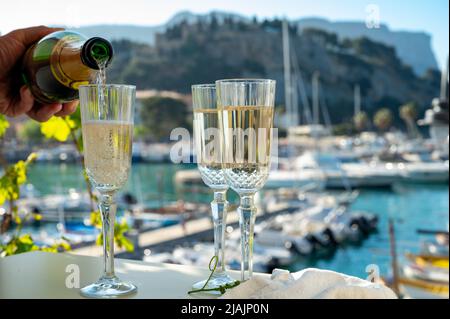 Drei Gläser französischen Champagner-Sekt und Blick auf bunte Fischerboote im alten Hafen von Cassis, Provence, Frankreich, Sommer Stockfoto