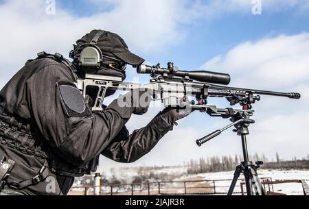 Scharfschütze mit teleskopischer optischer Sicht auf Scharfschützengewehr, das auf einem Stativ montiert ist. Stockfoto