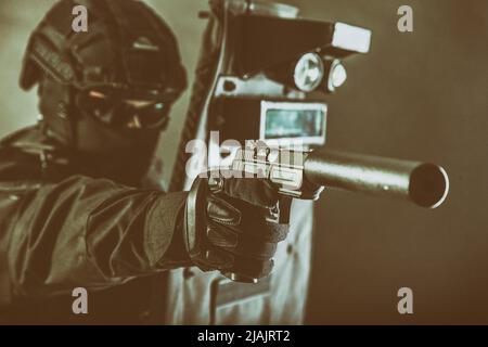 Polizei Spezialeinsätze Kämpfer mit Pistole mit Schalldämpfer ausgestattet, während sich hinter ballistischen Schild. Stockfoto