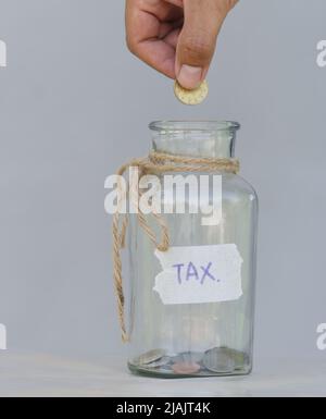 Hand Putting Münze in einem Glas mit Münzen auf weißem Hintergrund. Getrennt in Konzepte mit einer Sammlung von Geld, um in Reserve für Emergenci zu halten Stockfoto