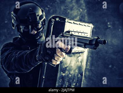 Der SWAT-Teamkämpfer zielte während eines Feuerkeldes mit einer Pistole von hinten auf ballistische Schauer. Stockfoto