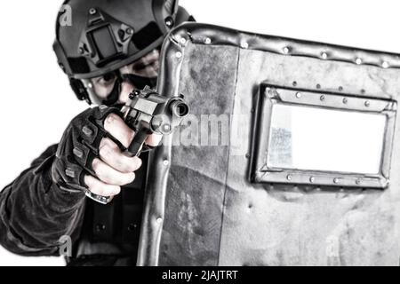 Der SWAT-Teamkämpfer zielte während eines Feuerkeldes mit einer Pistole von hinten auf ballistische Schauer. Stockfoto
