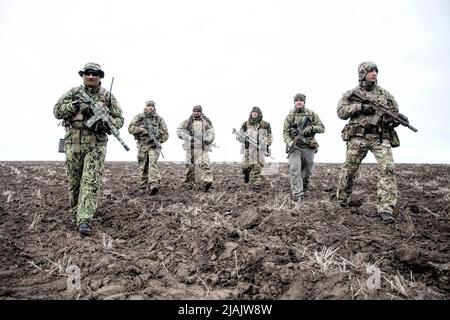 Soldaten gehen auf schlammigem Gelände Stockfoto