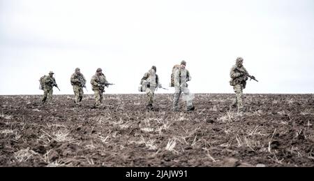 Soldaten gehen auf schlammigem Gelände Stockfoto