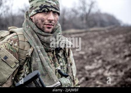 Portrait eines modernen Kämpelers mit schmutzigem Gesicht, trägt einen Beanie-Hut auf einem Feld stehend. Stockfoto