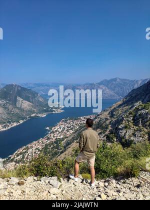 Der Mann steht und schaut von oben auf die Bucht von Kotor in Montenegro Stockfoto