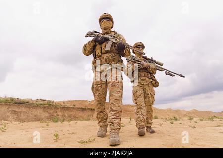 Ausgerüstete und bewaffnete Soldaten der Spezialeinheiten mit Gewehren während des Militärs Operation in der Wüste Stockfoto