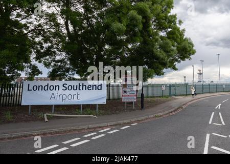 Ondon Southend Airport (SEN) und Sperrgebiet kein Stoppschild an der Straße zum Flughafen. Frau, die mit einer Tasche im Hintergrund läuft Stockfoto