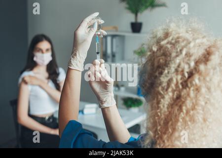 Krankenschwester in weißen Handschuhen, die die covid-19-Impfkrankheit für den Menschen vorbereiten. Arzt, der eine Dosis für einen Patienten mit dem dritten Impfstoff gegen Covid-19 vorbereitet Stockfoto