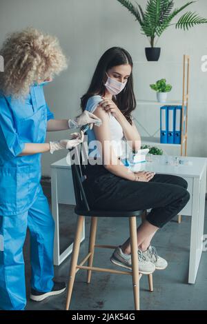 Frau, die von der Krankenschwester einen Impfstoff erhält und eine Spritze an den Patienten des Arms gibt. Coronavirus-Impfung. Impfungen, Impfungen, Konzept zur Prävention von Krankheiten Stockfoto