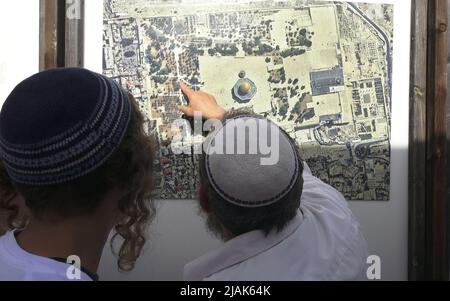 JERUSALEM, ISRAEL - MAI 29: Ultrarationalistische Israelis betrachten ein Luftfoto, das den Komplex des Felsendoms zeigt, bevor sie den Tempelberg besuchen, der den Muslimen als Haram esh-Sharif (Edles Heiligtum) bekannt ist. Während des israelischen Festes „Jerusalem Day“ vor dem jüdisch-nationalistischen „flaggenmarsch“ in der Altstadt am 29. Mai 2022 in Jerusalem, Israel. Der Flaggenmarsch zum Jerusalem-Tag markiert den Jahrestag der Vereinigung der Altstadt und Ostjerusalem im Jahr 1967. Stockfoto