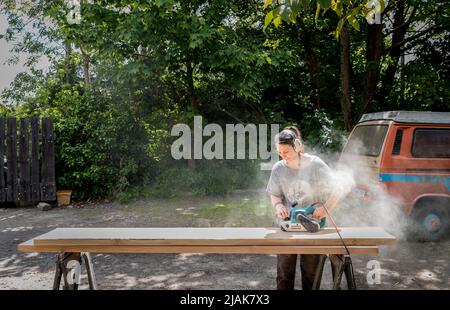 Bantry, Cork, Irland. 30.. Mai 2022. Die Holzarbeiterin Britta Faller schleift eine Douglas-Fir-Planke, die in der Beantree-Werkstatt außerhalb von Bantry, Co. Cork, Irland, zu einem Tisch gemacht wird. - Credit; David Creedon / Alamy Live News Stockfoto