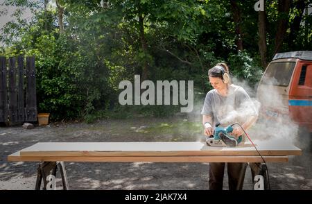 Bantry, Cork, Irland. 30.. Mai 2022. Die Holzarbeiterin Britta Faller schleift eine Douglas-Fir-Planke, die in der Beantree-Werkstatt außerhalb von Bantry, Co. Cork, Irland, zu einem Tisch gemacht wird. - Credit; David Creedon / Alamy Live News Stockfoto