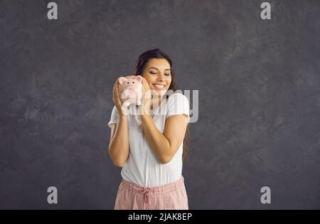 Lächelnde Lateinerin hält Sparschwein Stockfoto