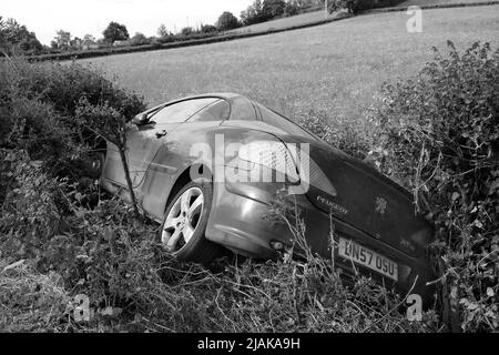 Mai 2022 - Peugeot Auto in einem Graben neben einer Landstraße das erste, was am Morgen nach einem Wochenende Stockfoto