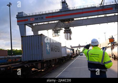 Hamburg, Deutschland. 30.. Mai 2022. In der Abendsonne transportiert ein Portalkran einen Container über das DUSS-Terminal in Hamburg Billwerder. Die deutsche Industrie geht nach wie vor davon aus, dass die Produktion in diesem Jahr unter den Bedingungen des Ukraine-Krieges, der Energieinflation und der Lieferkettenausfälle um knapp 2 Prozent wachsen wird. Quelle: Jonas Walzberg/dpa/Alamy Live News Stockfoto