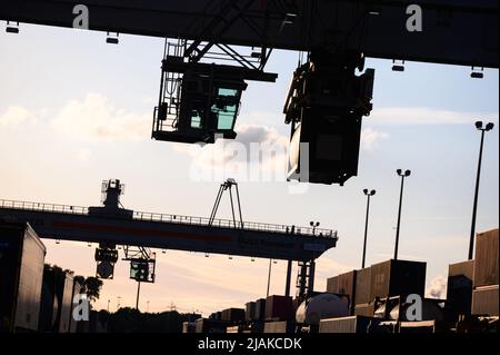 Hamburg, Deutschland. 30.. Mai 2022. Zwei Portalkrane transportieren Container vor der Abendsonne über das DUSS-Terminal Hamburg Billwerder. Die deutsche Industrie geht nach wie vor davon aus, dass die Produktion in diesem Jahr unter den Bedingungen des Ukraine-Krieges, der Energieinflation und der Lieferkettenausfälle um knapp 2 Prozent wachsen wird. Quelle: Jonas Walzberg/dpa/Alamy Live News Stockfoto