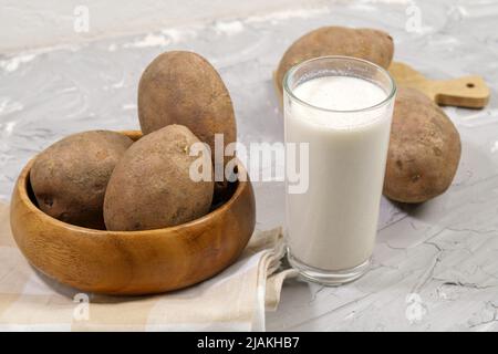 Glas mit Kartoffelmilch zur Kartoffel. Trend in gesunder Ernährung. Alternative Lebensmittel. Gesunde Pflanzenmilch. Stockfoto