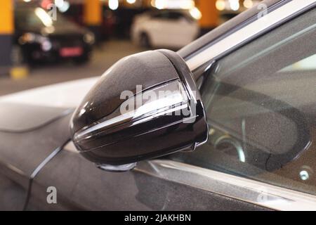 Moderner Klappspiegel mit Blinker. Schwarzes Auto, Nahaufnahme. Außen Stockfoto
