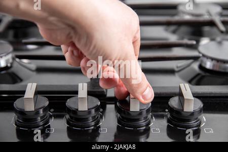 Die Hand eines Mannes schaltet ein Gaskochfeld an. Gas-Sanktionskonzept, Schutz vor Kindern. Gasherd mit elektrischer Zündung. Stockfoto