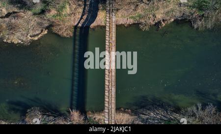 Drohnenfoto von Industriegebäuden Europaletten in der Nähe des Flusses und der Brücke Stockfoto