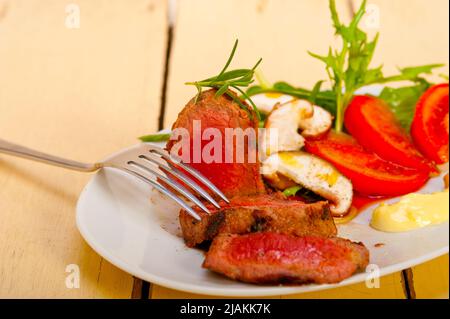 Rindfleisch Filet Mignon gegrillt mit frischem Gemüse auf Seite, Pilze, Tomaten und Rucola Salat Stockfoto