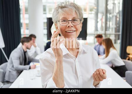 Lächelnde Geschäftsfrau, die sich auf dem Smartphone im Konferenzraum unterhielt Stockfoto