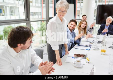 Lächelnde Geschäftsfrau als Sprecherin am Konferenztisch nach einer Präsentation in der Sitzung Stockfoto