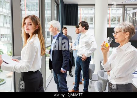 Junge Frau als Auszubildende und Kollegen bei einer Kaffeepause am Fenster im Büro Stockfoto