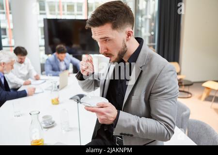 Im Konferenzraum trinkt der junge Geschäftsmann als Gründerin eine Tasse Kaffee Stockfoto