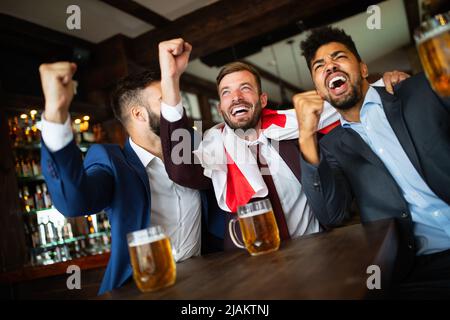 Männerfans schreien und beobachten Fußball im Fernsehen und trinken Bier in einer Kneipe Stockfoto