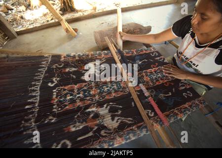 Eine Frau, die in der Werkstatt von Ama Nay Tukang, einem berühmten Händler von traditionellen sumbanesischen Geweben, in Waingapu, East Sumba, East Nusa Tenggara, Indonesien, webt. Stockfoto