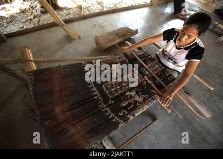 Eine Frau, die in der Werkstatt von Ama Nay Tukang, einem berühmten Händler von traditionellen sumbanesischen Geweben, in Waingapu, East Sumba, East Nusa Tenggara, Indonesien, webt. Stockfoto