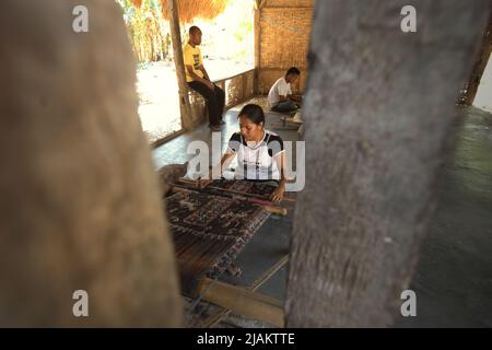 Eine Frau, die in der Werkstatt von Ama Nay Tukang, einem berühmten Händler von traditionellen sumbanesischen Geweben, in Waingapu, East Sumba, East Nusa Tenggara, Indonesien, webt. Stockfoto