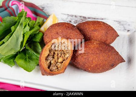 Kibbeh auf weißem Holzhintergrund. Kibbeh ist ein beliebtes Gericht in der nahöstlichen Küche. Gefüllte Fleischbällchen Essen, Falafel, icli Kofta, Quibe. Draufsicht. E Stockfoto